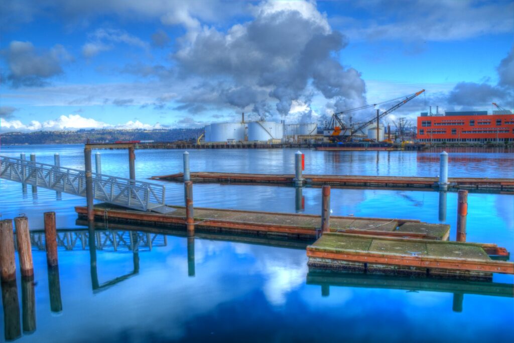 Ultra blue water with white and blue cloud reflections, fishing piers and docks, and white cumulus clouds floating above Commencement Bay, Tacoma, WA