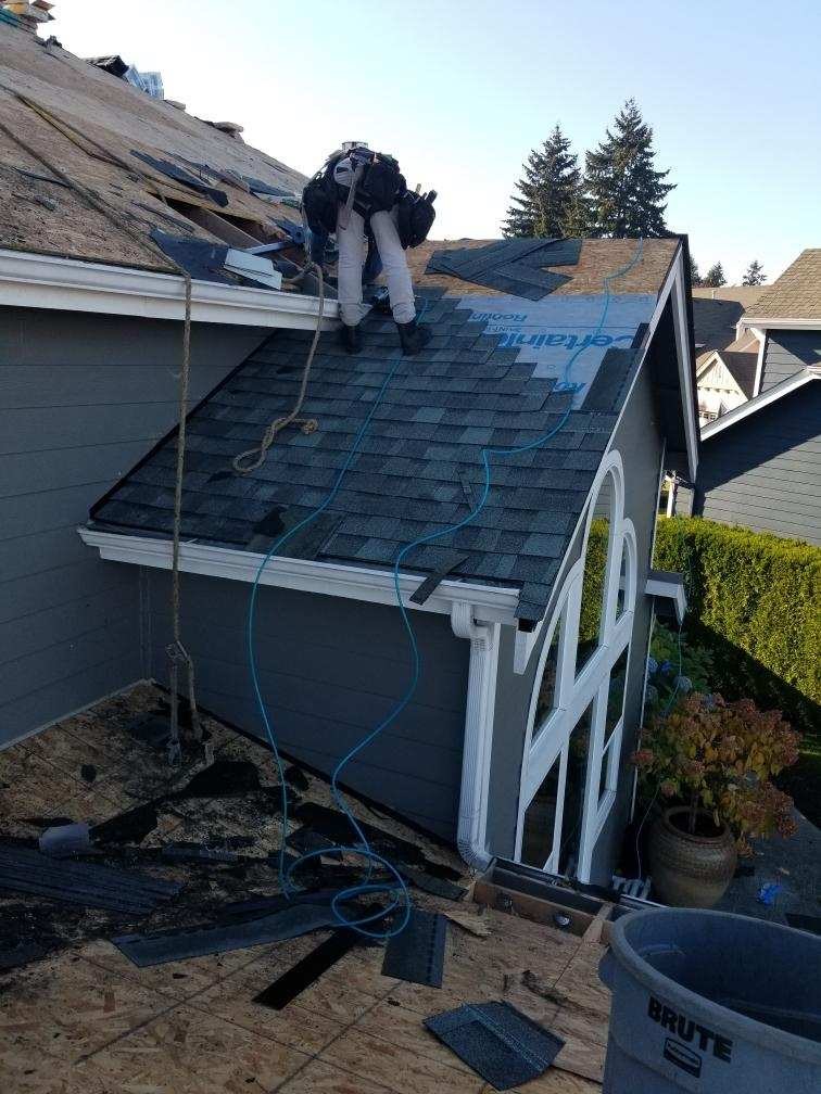 Roofers installing new shingles to complete a roof replacement project