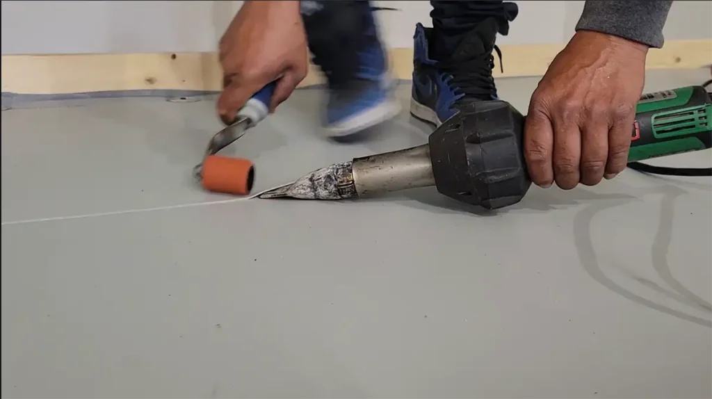 Three Tree Roofing Roofer demonstrating welding overlapping pieces of membrane with a leister.