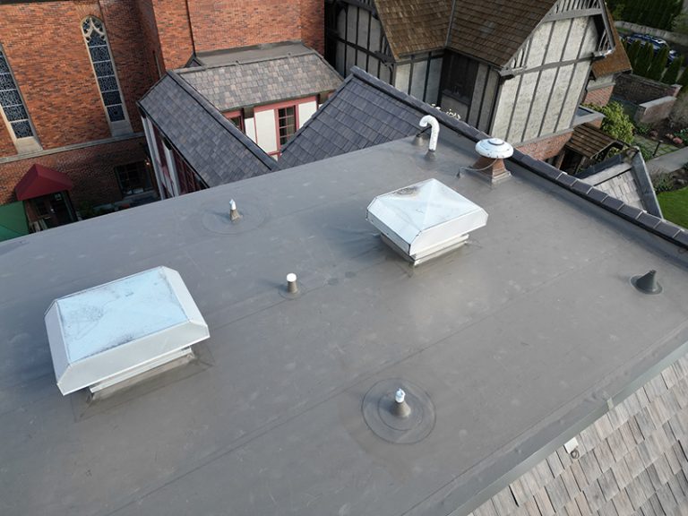 View of top roof details of a building with a Synthetic Shake Shingle Church and School Roof in Seattle, Washington